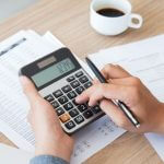 Homem usando uma calculadora, representando o tema como administrar o seu dinheiro.