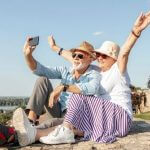 Casal de idosos felizes tirando uma selfie, representando o tema aproveitar a terceira idade.