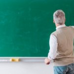 Servidor estadual escrevendo em um quadro da escola que trabalha