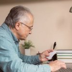 homem anotando as condições do refinanciamento no computador