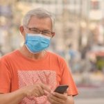 Idoso sorrindo enquanto mexe no celular, explorando opções de empréstimo consignado.