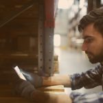 Homem no trabalho mexendo no celular, buscando informações sobre saque-aniversário.