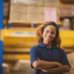 Mulher sorrindo no trabalho, refletindo sobre quem pode antecipar o saque-aniversário.
