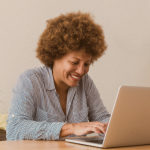 Mulher sorrindo enquanto mexe no computador, interessada em empréstimo consignado.