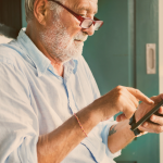 Idoso mexendo no celular prazo para pagamento do empréstimo consignado