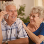 alt="idosos sorrindo ao telefone"