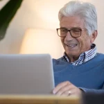 Idoso mexendo no computador como funciona empréstimo para aposentados