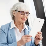 Idosa usando o celular guia para o recém-aposentado