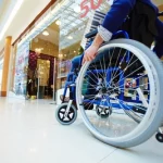 Imagem de uma pessoa com cadeira de rodas andando pelo shopping.