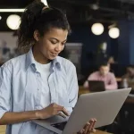 Mulher sorrindo enquanto usa o computador, ilustrando o processo de pagamento de férias pela CLT.