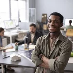 Homem no trabalho, com os braços cruzados e sorrindo, representando o código 1406 INSS.